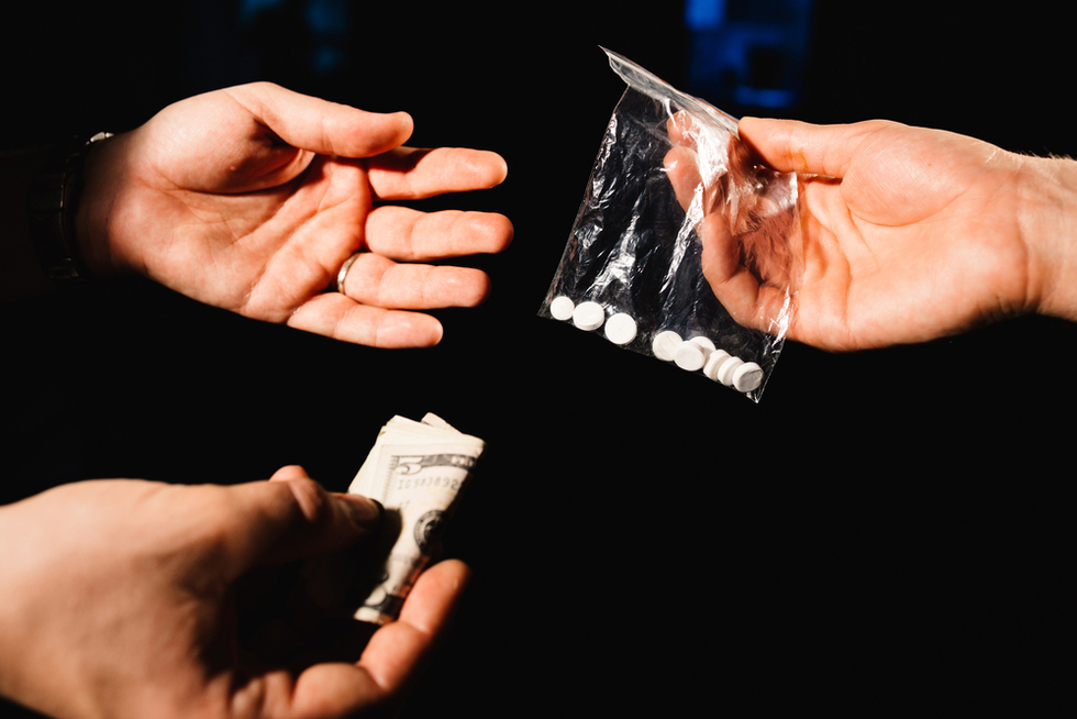 ecstasy pills, cash, and hands and an example of violating Nevada drug sales laws