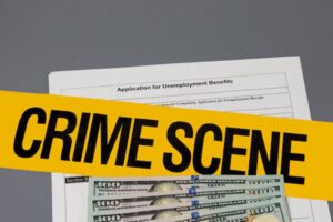 Unemployment benefits application with yellow crime scene tape against a grey background
