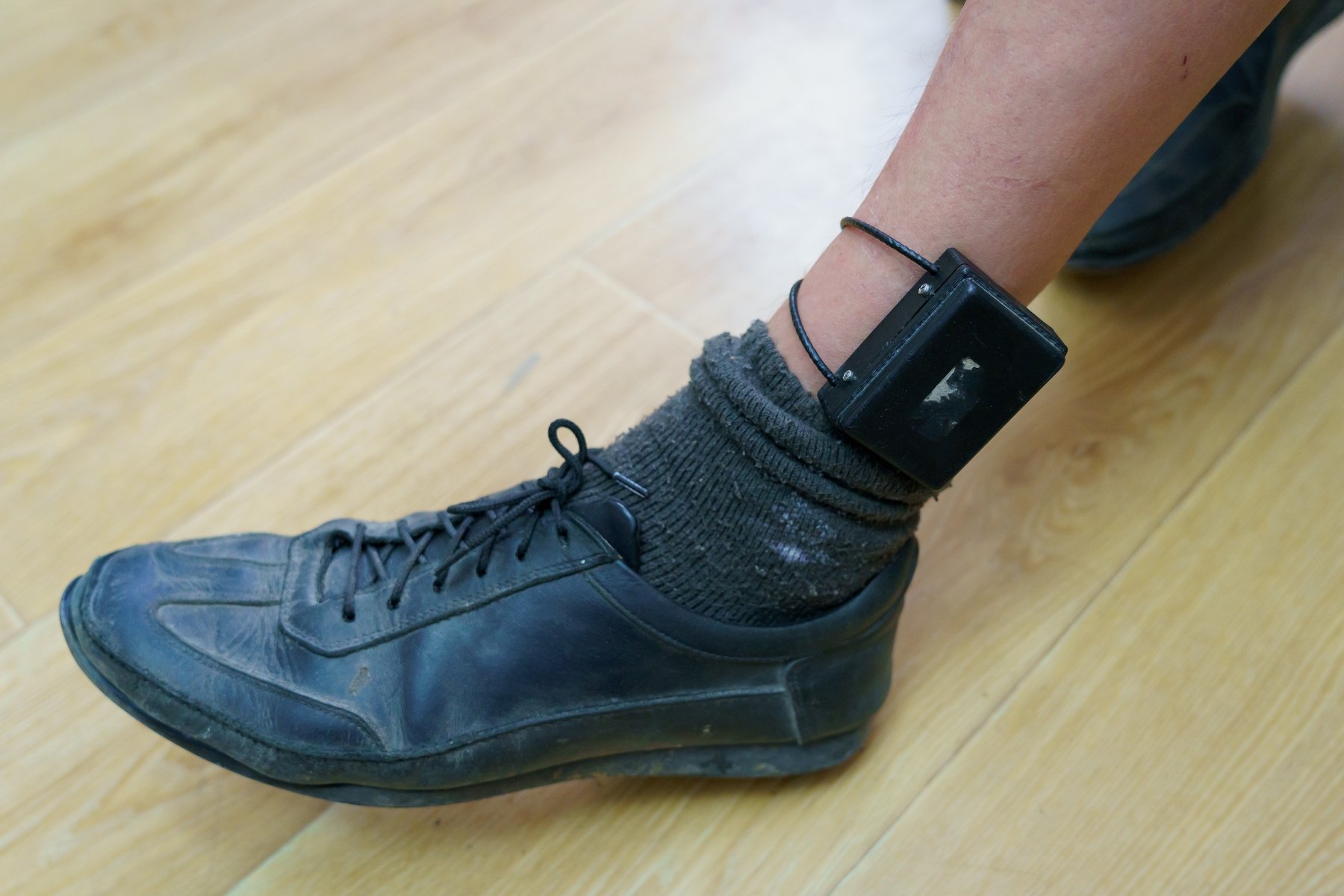 Closeup of a man's leg with an ankle monitor tracking his whereabouts