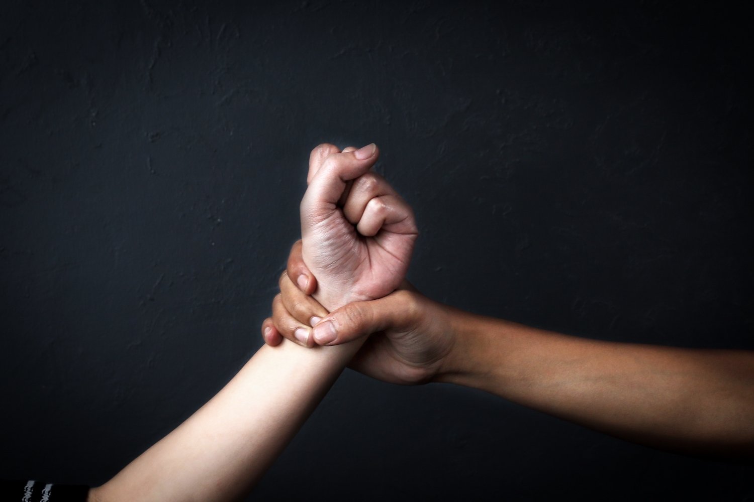 Man's hand in fist about to inflict an act of domestic violence as victim grasps his wrist