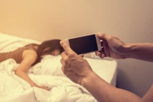 Hand man holding phone to photograph woman in bed as blackmail in violation of NRS 205.320 