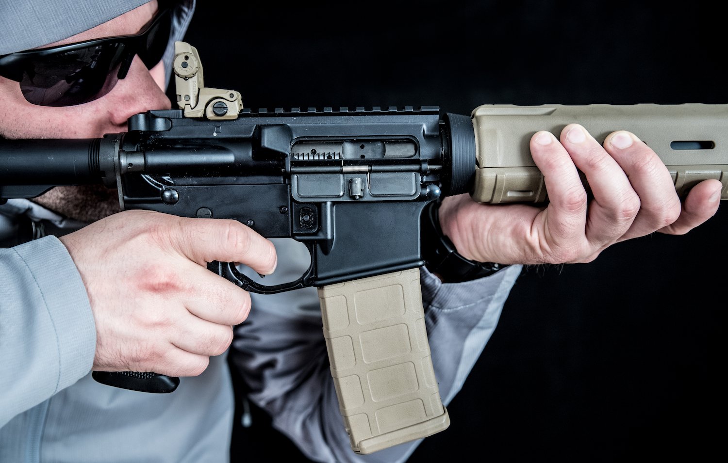 Man holding an automatic weapon against a black background