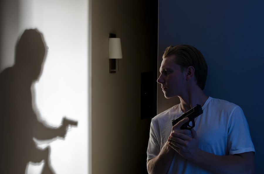 Homeowner holding gun who sees shadow of burglar with gun 