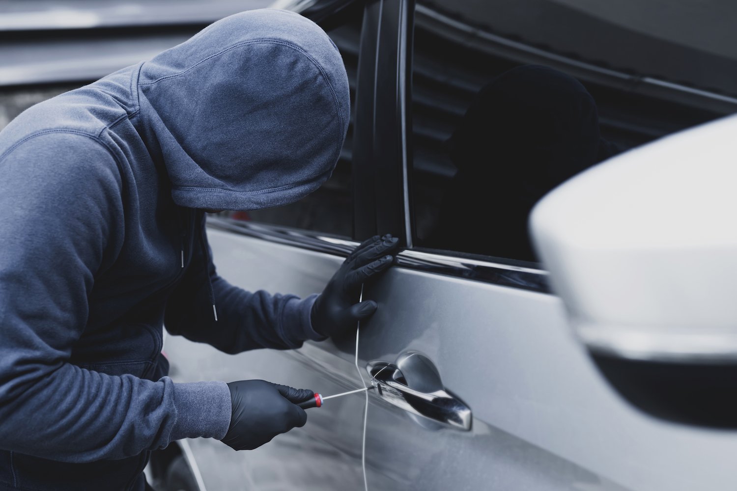 Hooded burglary breaking into a sedan on the street
