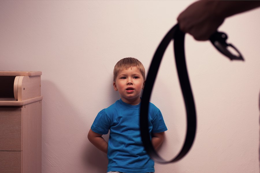 Child against while with parent's hand holding belt prior to inflicting corporal punishment