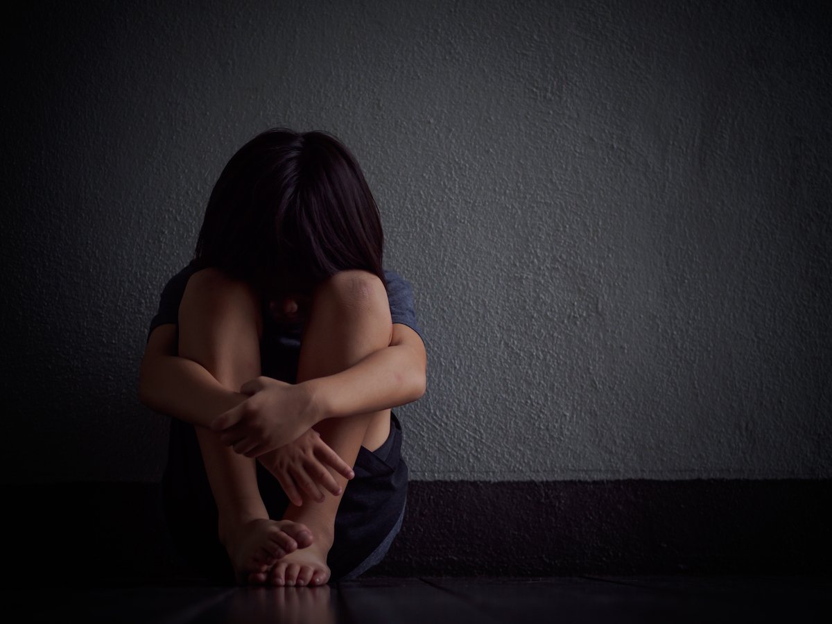 Neglected young girl sitting in a dark room