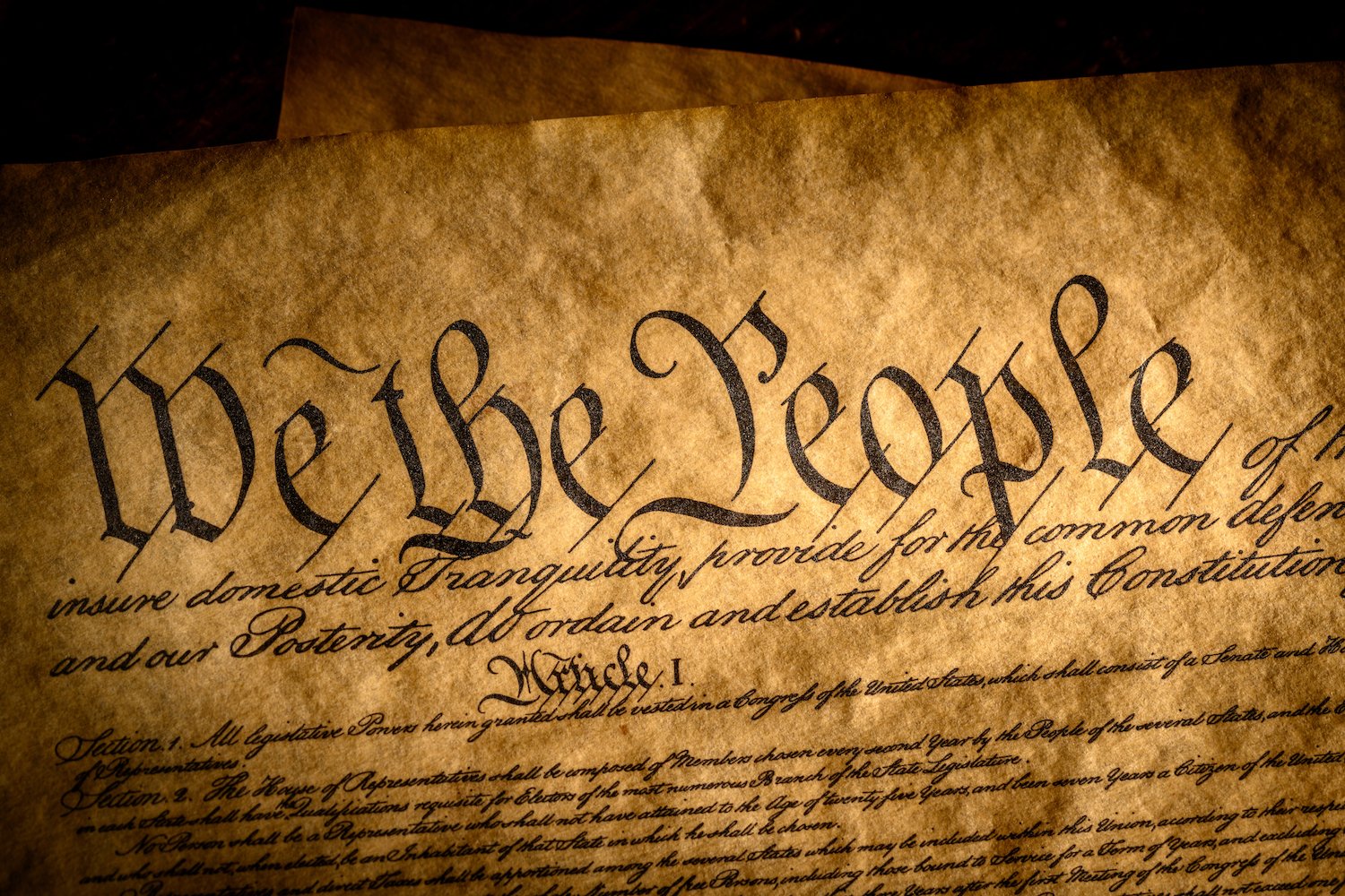 The beginning of the Constitution, "We the People" on aged yellow scroll paper