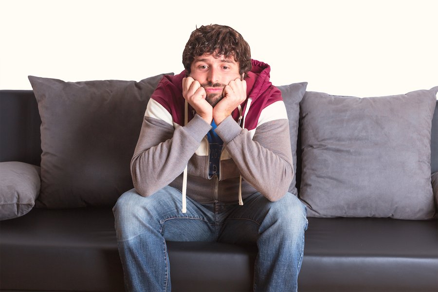 Man on house arrest sitting bored on couch