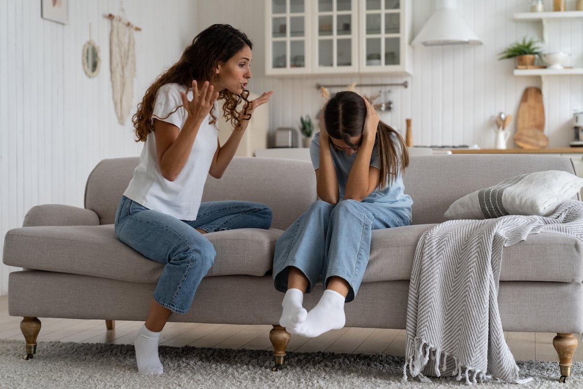 Angry mother yelling at her child on the living room couch