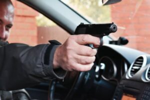 Man aiming gun out of vehicle