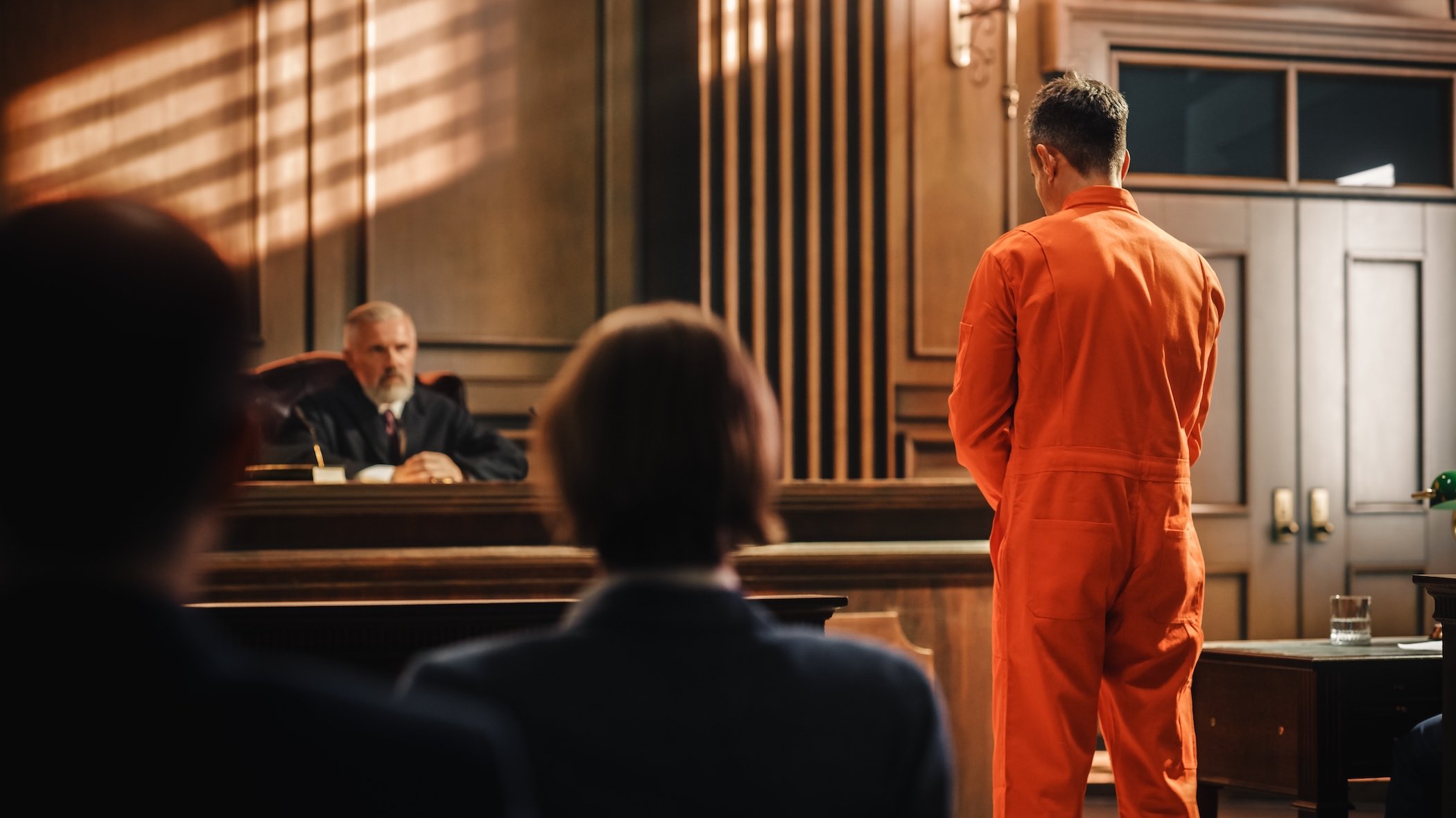 Inmate in orange jumpsuit in a courtroom being arraigned by the judge following a DUI arrest
