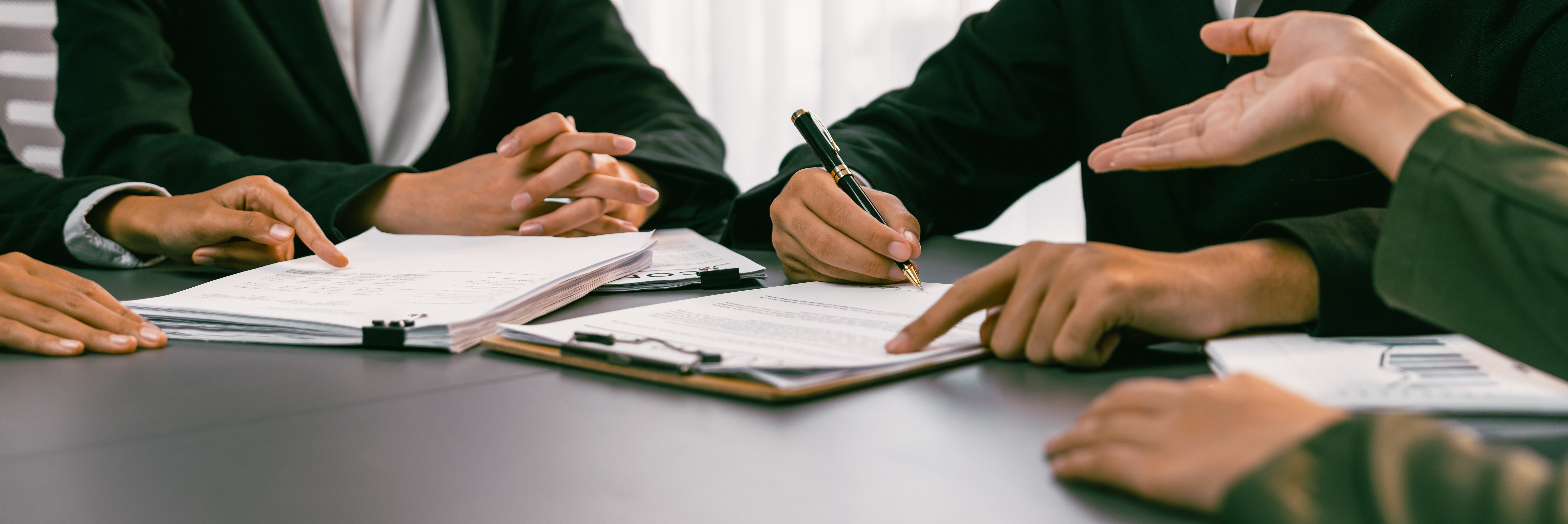 Group of attorneys negotiating at a table with clipboards and pens