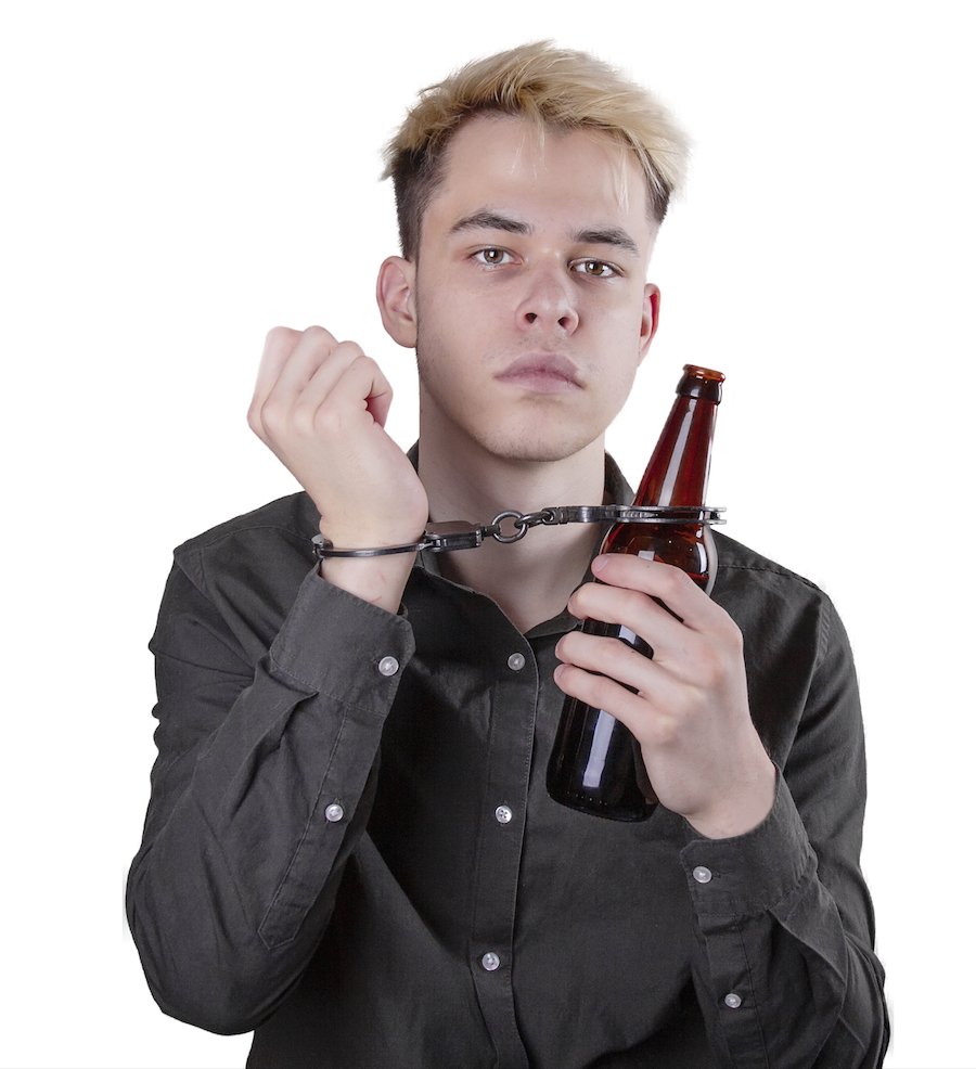Teenager handcuffed to a bottle of beer against a white background