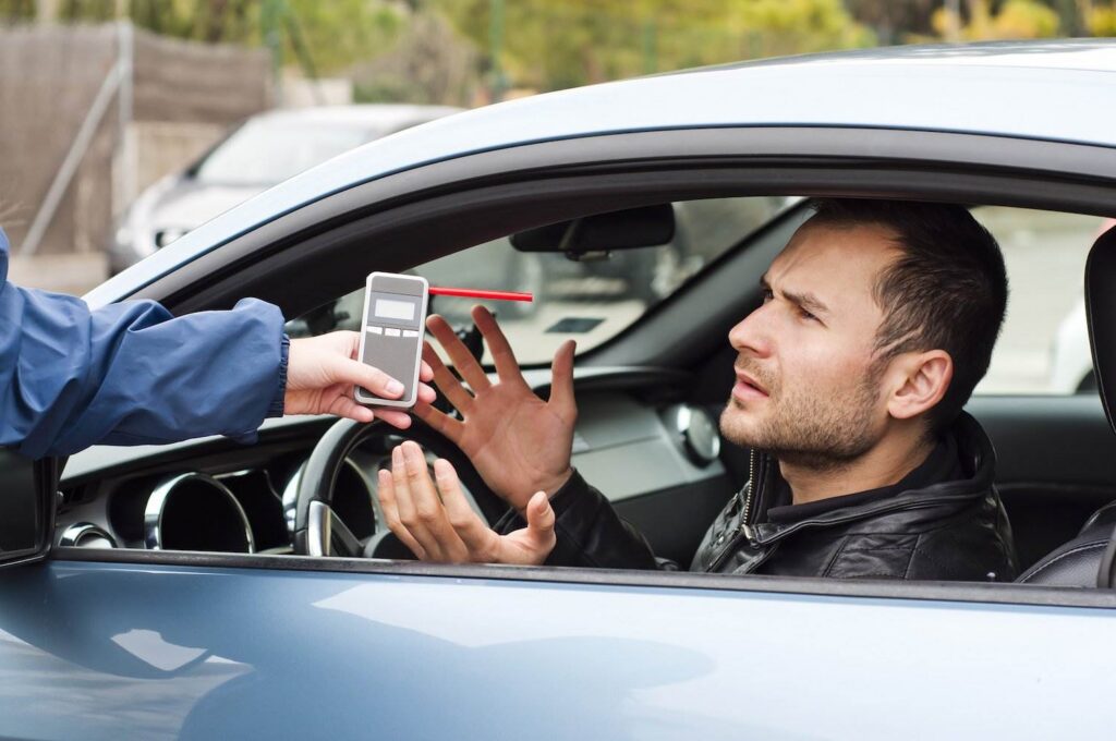 Man in car arguing with police about taking a preliminary breath test. 