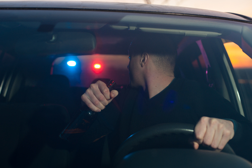 Driver looking through his rear windshield at a police signalling him to pull over