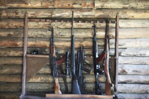 Several rifles leaning against a log cabin wall