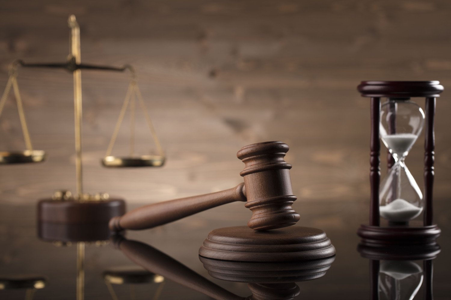 Scales of justice, judge's gavel, and hourglass on a table