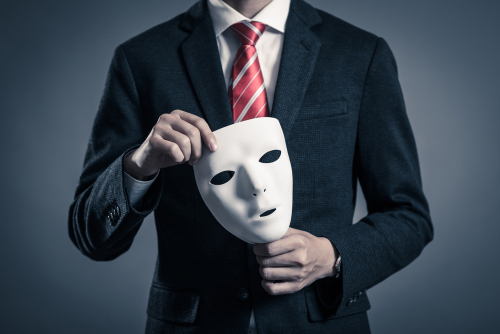 man in suit holding a face mask