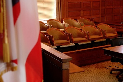 A jury box in a courtroom prior to a trial, with an American flag in the foreground
