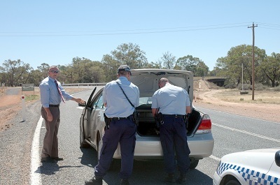 Police searching trunk of automobile by the side of a road