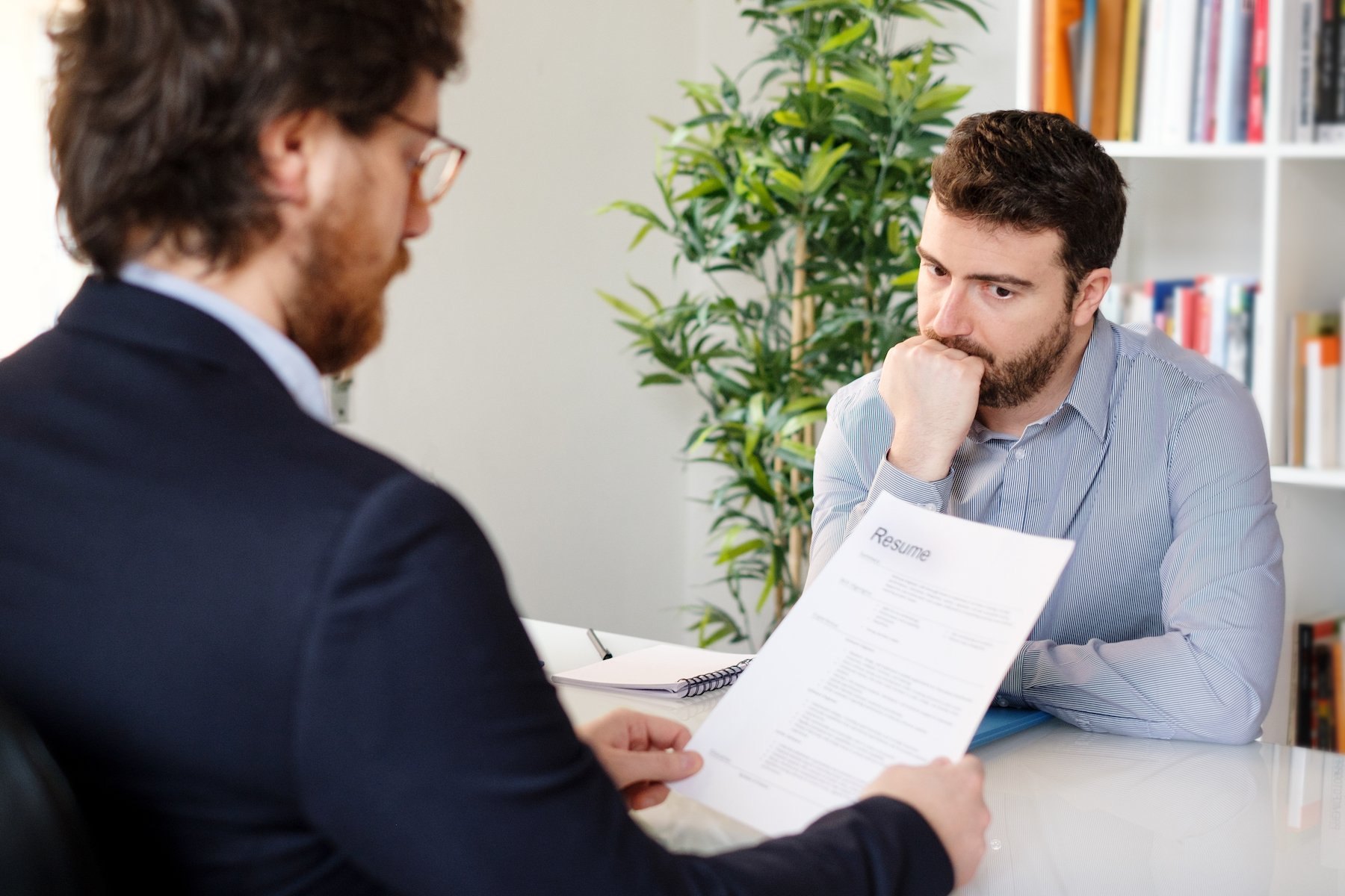 Nervous job applicant during an interview where the hiring agent is looking over his background check and resume