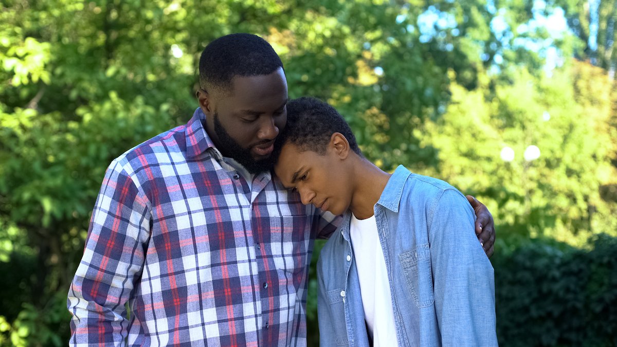 Father comforting his son following his juvenile court hearing with trees in the background