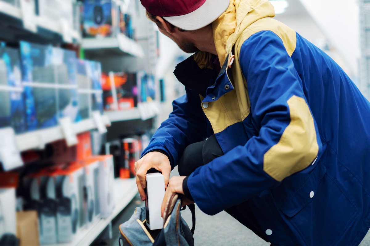 Shoplifter taking an expensive hard drive and putting it into his backpack