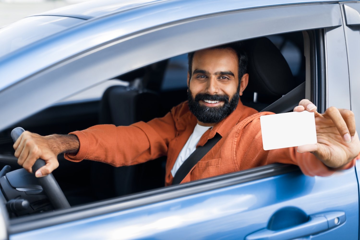 Happy driver in the driver's seat showing off his driver's license