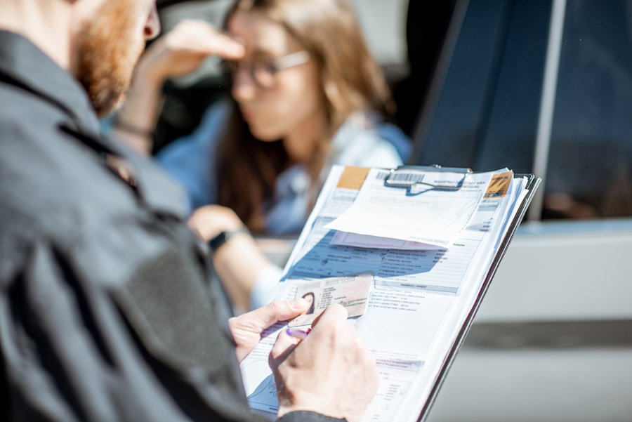 Police officer writing up a driver during a traffic stop after officer realized her license was revoked
