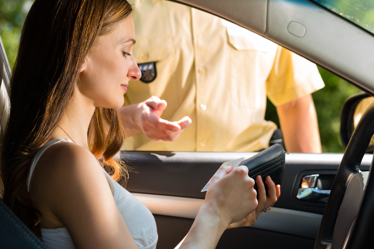 Woman driver giving her suspended driver's license to a police officer during a traffic stop