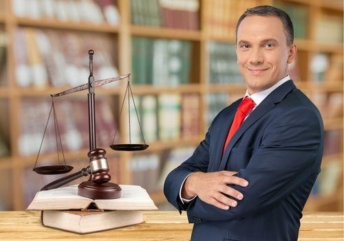 Male attorney next to scale of justice