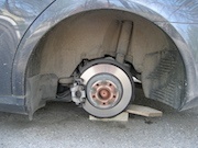 A close-up of where a wheel is missing from a car