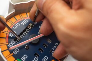 Man tampering with an odometer by using a sharp tool