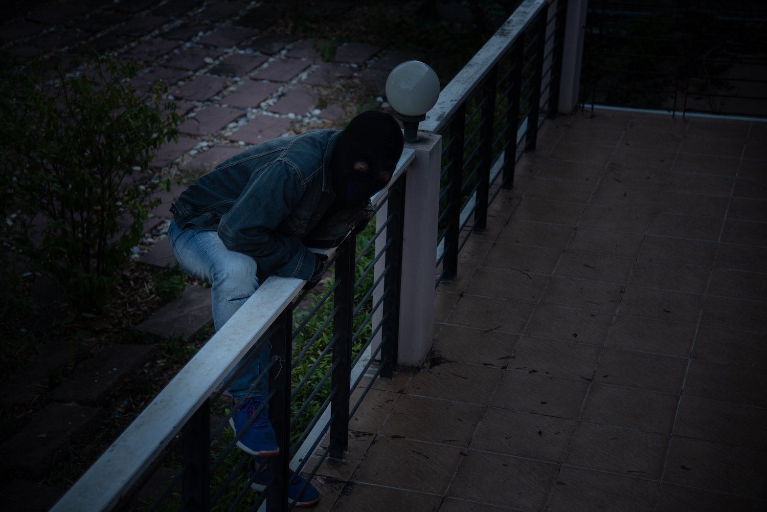 Hooded burglary scaling a patio fence to enter the house and steal from it