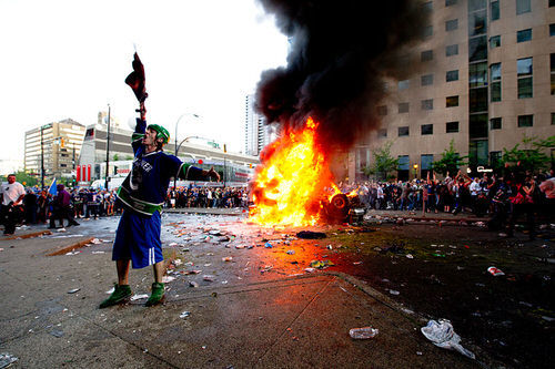 Man rioting on street corner in front of fire 