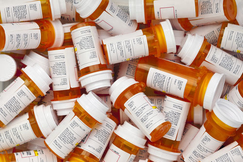 Piles of empty prescription pill bottles.