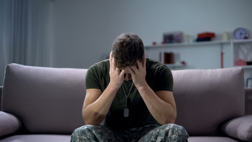 A veteran lowering his head into his hands in anguish.