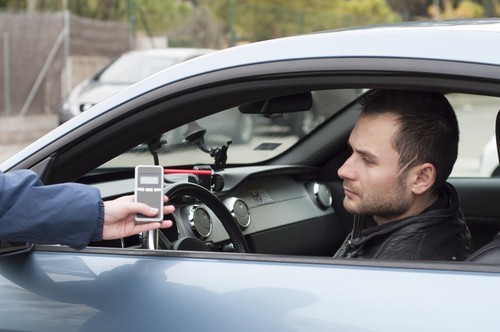 preliminary breath test being administered by police officer to a dejected DUI suspect