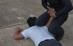 Police conducting an arrest but putting his knees on the arrestee's back. 