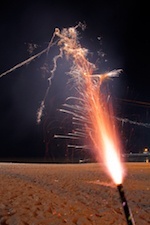 sparkler firework on sandy ground at night