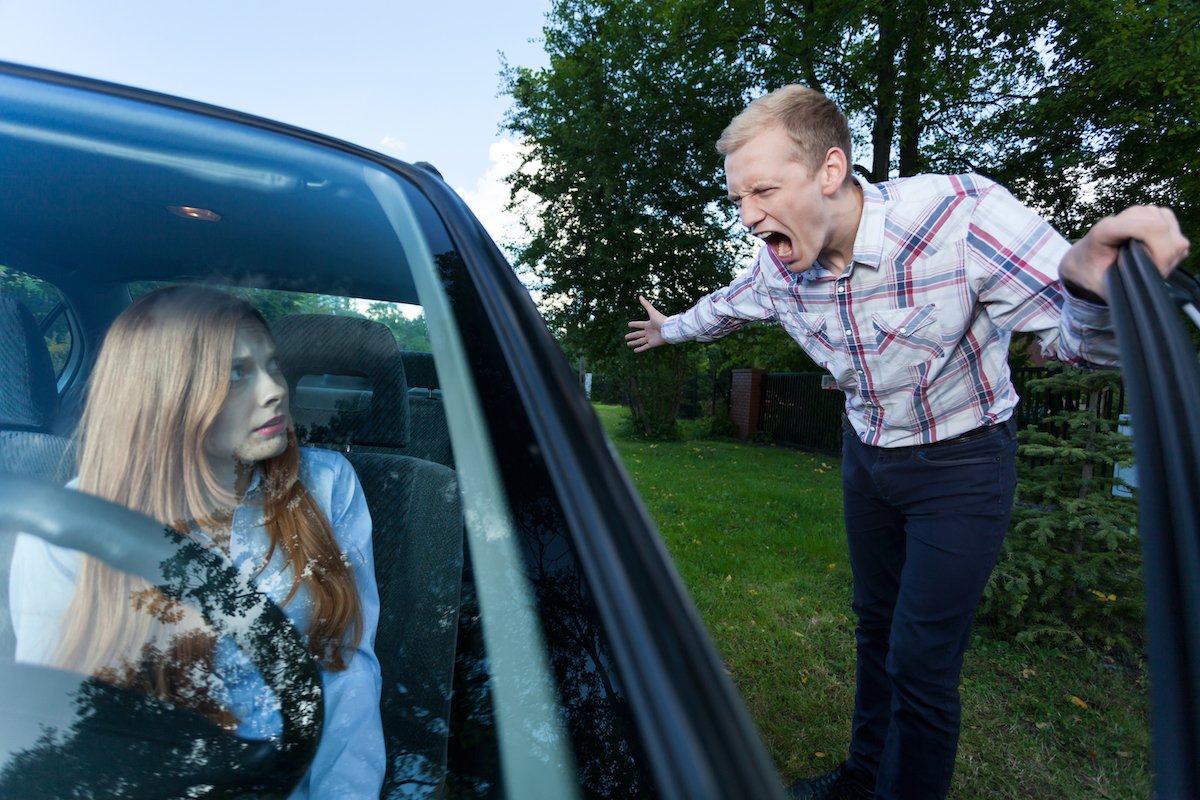 Man screaming at woman driver on the side of a road during a road rage incident