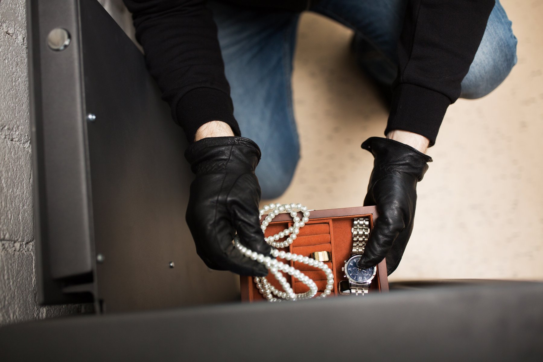 Thief in black leather gloves stealing jewelry from a safe in violation of NRS 205.220