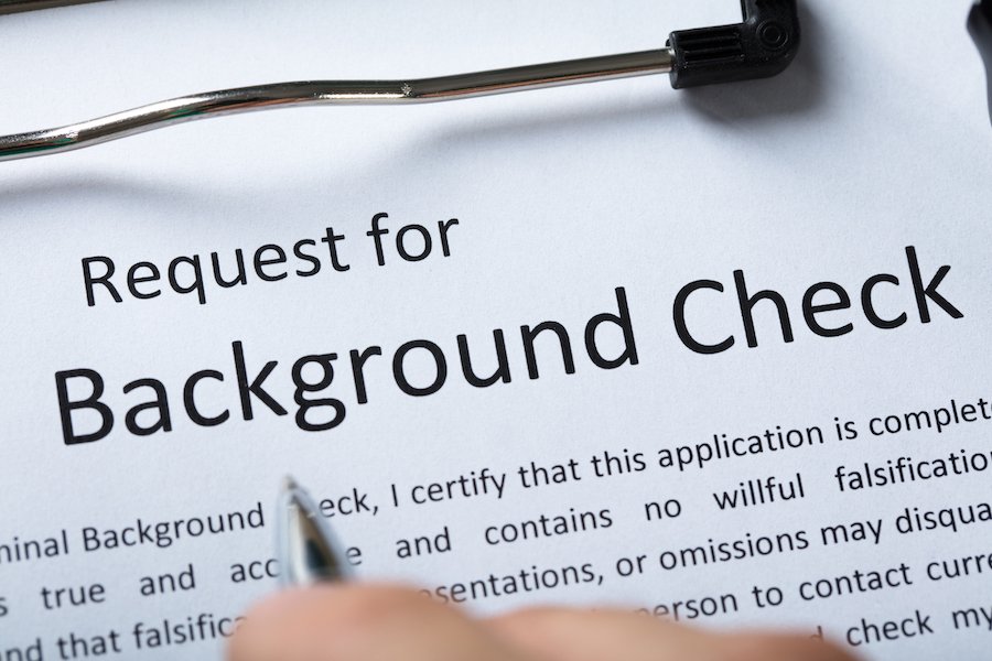 Closeup of "request for background check" on a clipboard with a job applicant's hand over it