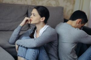 Married couple sitting down but facing away from each other after having a difficult discussion
