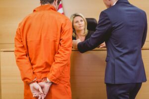 Defendant in orange jumpsuit next to attorney trying to convince judge to give defendant another chance after he violated his stay of adjudication terms