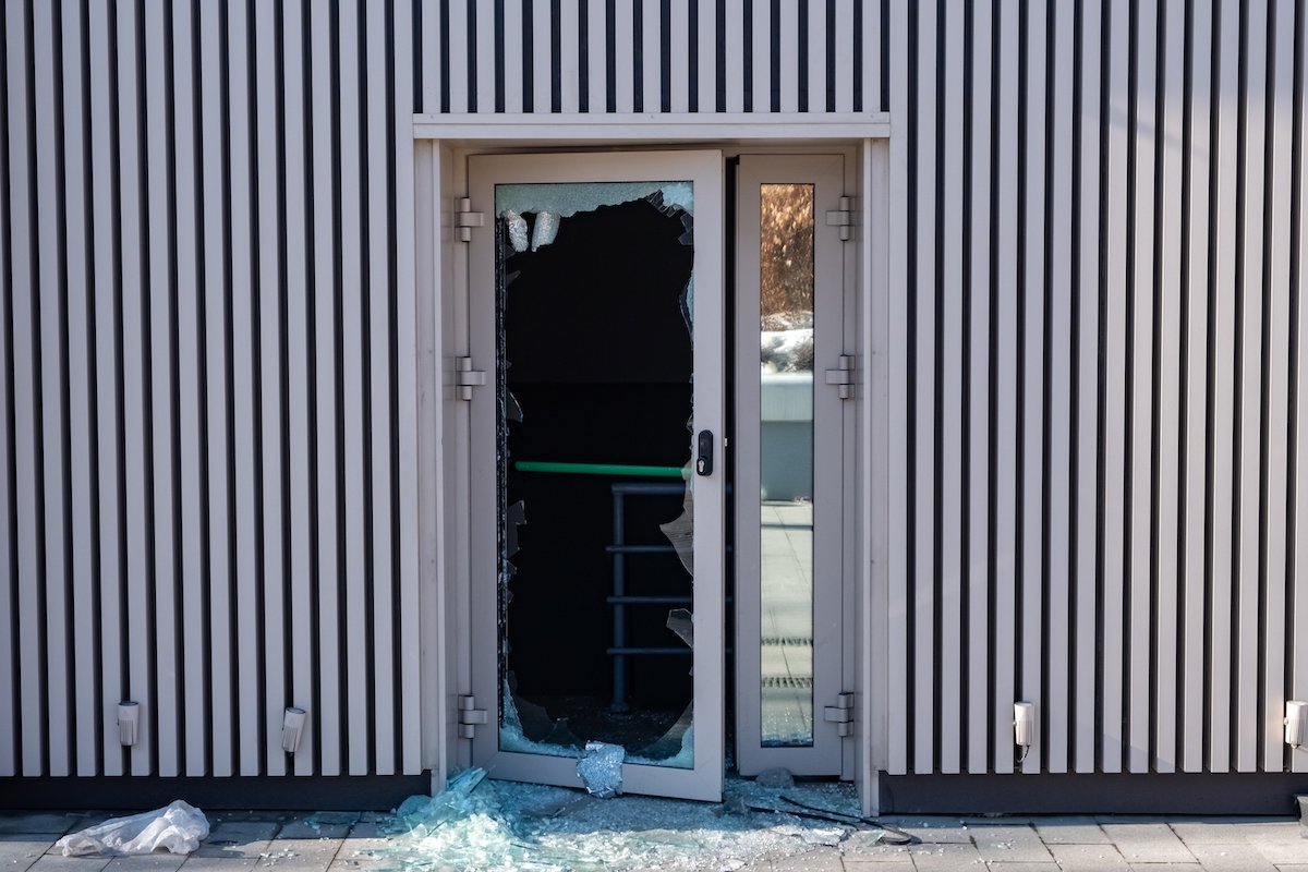 Store door that has been broken into with shattered glass on the ground