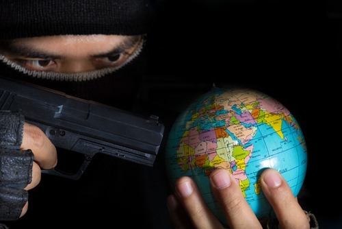closeup of masked man holding a handgun at a small globe he is holding in his other hand, symbolizing an NRS 202.448 violation