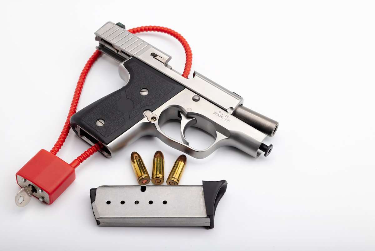 Handgun with a lock mechanism on the trigger against a white background