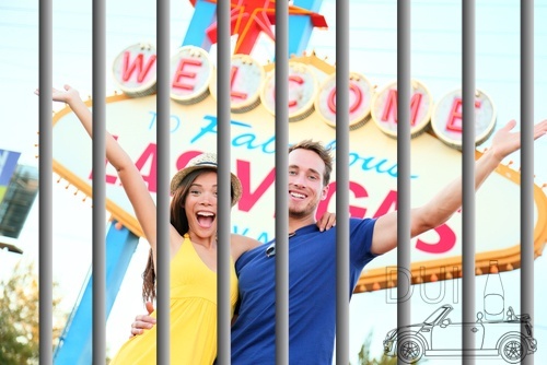 Couple in front of the 'Welcome to Las Vegas' sign with jail bars in the foreground